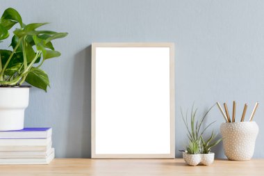 Kitap, şık pot ve tillandsia tasarım tencere güzel bitki ile kahverengi ahşap masada fotoğraf çerçevesi kadar sahte minimalist ev iç. Gri duvarlar. Masanın minimal dekoru.
