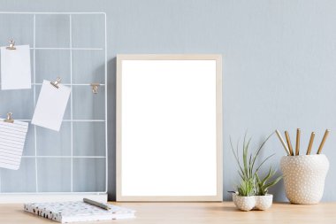 Ofis aksesuarları, dizüstü bilgisayarlar ve tillandsia tasarım kapları ile kahverengi ahşap masa üzerinde sahte fotoğraf çerçevesi ile minimalist ev iç. Gri duvarlar. Masanın minimal dekoru.