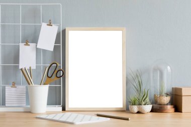 Ofis aksesuarları, tasarım kaplar, defter ve notlar tillandsia ile kahverengi ahşap masa üzerinde sahte fotoğraf çerçevesi ile yaratıcı masanın ev iç. Gri duvarlar. En az maket kavramı.
