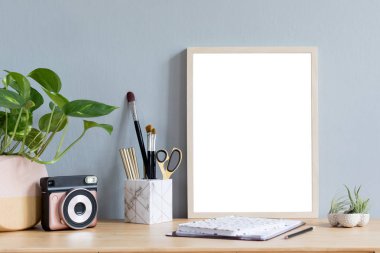 Ofis aksesuarları, anlık kamera, tasarım tencere tillandsia ile kahverengi ahşap masada sahte fotoğraf çerçevesi ile şık ev iç, şık tencere bitki. Gri duvarlar. En az maket kavramı.