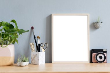 Ofis aksesuarları, anlık kamera, tasarım tencere tillandsia ile kahverengi ahşap masada sahte fotoğraf çerçevesi ile şık ev iç, şık tencere bitki. Gri duvarlar. En az maket kavramı.