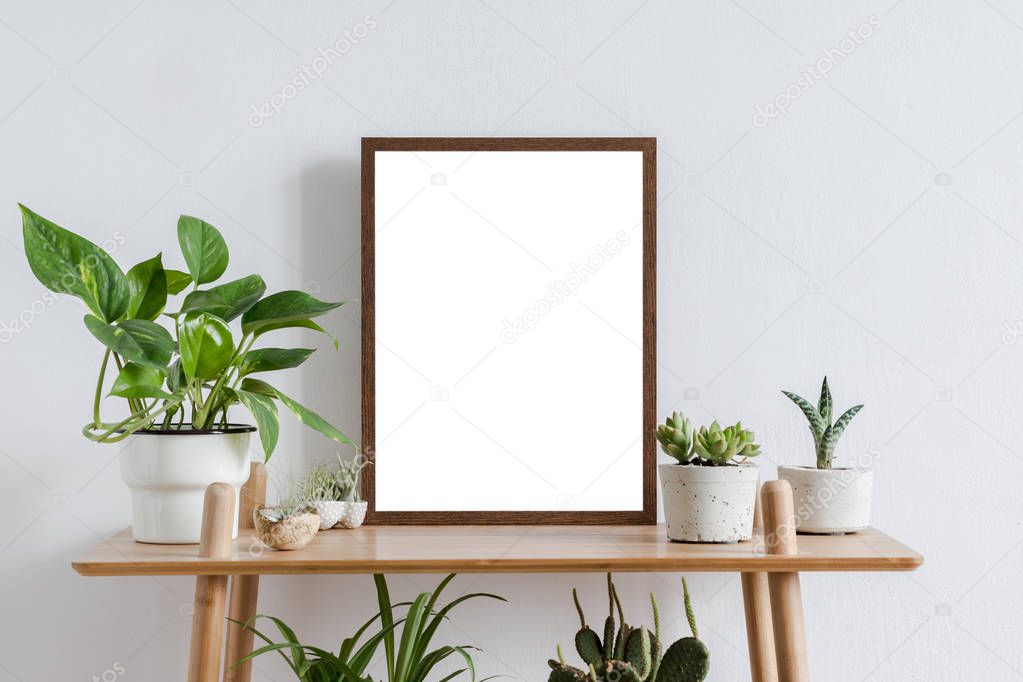 Scandinavian room interior with mock up photo frame on the brown bamboo shelf with beautiful plants, green leafs and accessories. White walls. Modern and floral concept of shelfs.