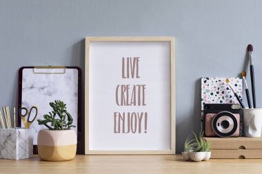 Ofis aksesuarları, kutular, anlık kamera, şık pot güzel bitki ile kahverengi ahşap masada fotoğraf çerçevesi kadar sahte İskandinav ev iç. Gri duvarlar. Masanın minimal dekoru.