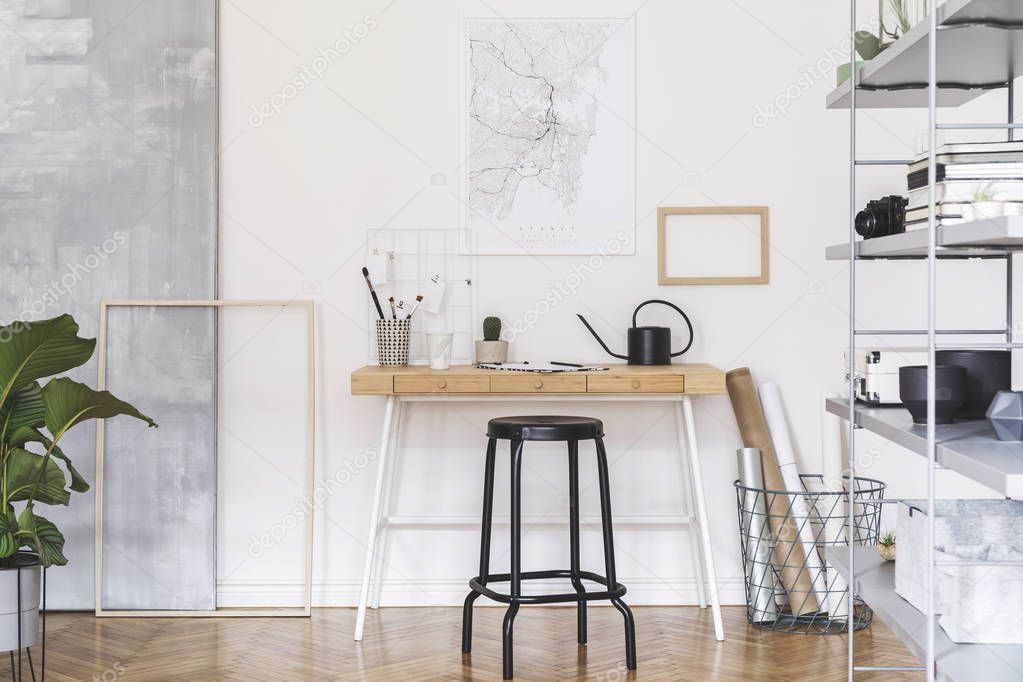 Stylish nordic home interior with wooden desk, grey and white bookstand with accessories, design and modern furniture. Open space and living room for artist, freelancer. Mockup poster frame