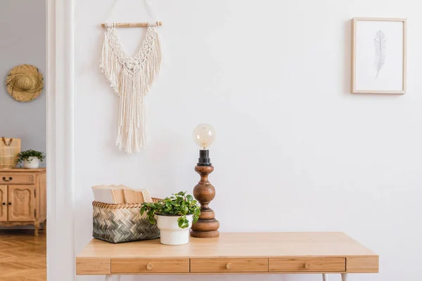 Ahşap masa, bej macrame, tasarım aksesuarları, masa lambası, kitap ve sahte fotoğraf çerçevesi ile oturma odası şık bohem iç, Tasarım kadın odası Parçası. Tasarım ev dekorasyonu
