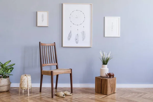 Modern bohemian interior design of living room with retro chair, rattan lamp, wooden cube, plants, flowers, mock up poster frames and elegant accessories. Stylish home decor. Template. Gray walls