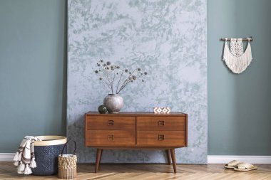 Ahşap retro komodin, çiçek, makrame, soyut arka plan duvarları, rattan sepeti ve zarif aksesuarları ile vazo ile oturma odası minimalist ve boho kompozisyon. Modern ev dekorasyonu. Şablon