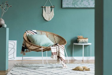 Tasarım rattan koltuk ve zarif aksesuarları ile oturma odası şık minimalist iç. Duvarın okaliptüs rengi. Kopyalama alanı