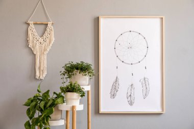 Poster çerçevesi, retro sandalye, ahşap masa, tropikal bitkiler, gri makrame ve zarif aksesuarlar ile sahte oturma odası şık ve boho kavramı. Modern iç tasarım. Güzel ev dekorasyonu. Şablon