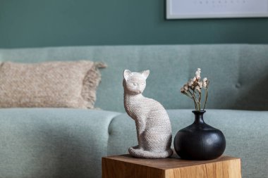 Tasarım heykelinin şık ve şık kompozisyonu, tahta küpünde çiçekler olan vazo. Zarif aksesuarlar. Şablon. Oturma odasında naneli kanepeli iç tasarım. Parlak ve güneşli bir alan.