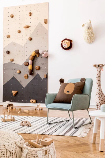 Modern scandinavian interior design of childroom with mint armchair, climbing wall for kids, design furnitures, soft toys, teddy bear and cute children\'s accessories. Stylish kidroom decor. Template.