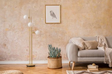 Altın lambalı iç mekan, tasarım gri kanepe, resim çerçevesi, kitaplar, bitki, halı, rattan pouf, yastık, ekose ve zarif aksesuarlar ev dekorunda..