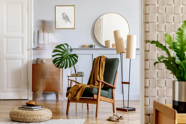 Stylish interior of living room with design armchair, wooden vintage commode, round mirror, shelf, tropical leaves, coffee table, decoration, carpet and persnoal accessories in home decor.