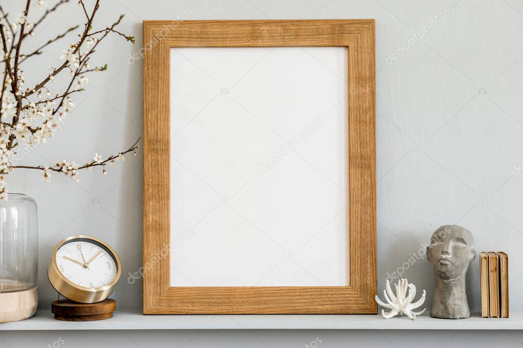 Minimalistic concept on the shelf with brown mock up photo frame, dired flower in vase, gold clock, book and elegant personal accessories at stylish home interior.