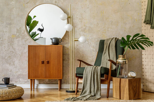 Stylish composition of living room interior with design armchair, lamp, rattan pouf, commode, tropical leaves, plaid, carpet, mirror and elegant presonal accessories in modern retro concept.