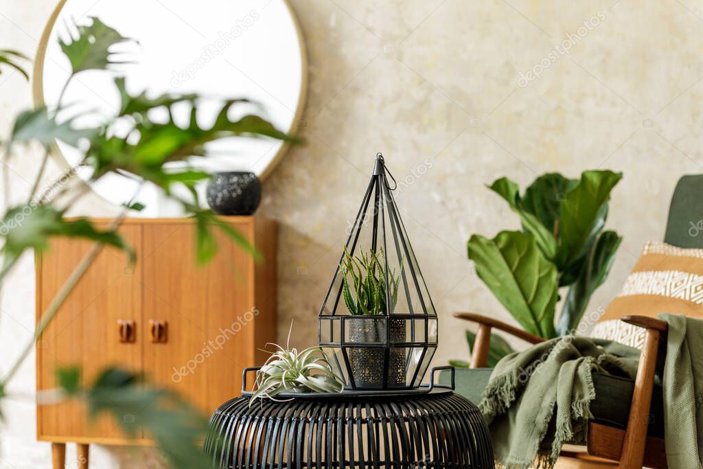 Stylish composition at modern retro interior with rattan coffe table, round mirror, a lot of plants, armchair, lantern, commode, pillow, plaid and elegant personal accessories in home decor.