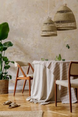 Lokanta masası, tasarım koltukları, rattan kolye lambaları, tropikal bitki, halı, dekorasyon ve Wabi Sabi konseptinde zarif kişisel aksesuarları olan şık ve şık bir yemek odası..
