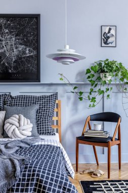 Moda koltuğu, poster çerçeveleri, kitap, saat, dekorasyon, halı, güzel yatak çarşafları, battaniye ve yastıklar modern ev dekorunda..