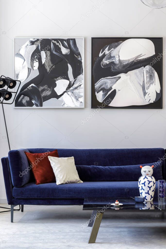 Stylish and modern living room interior with blue velvet sofa, mock up paintings, design furniture, plant, table, decoration, concrete floor, elegant personal accessories in home decor.