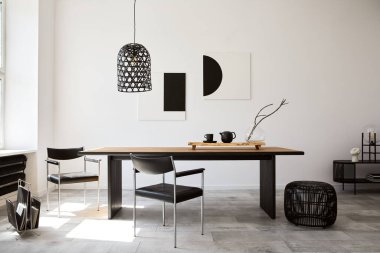 Tasarım ahşap aile masası, siyah sandalyeler, fincanlı çaydanlık, duvarda sanat resimleri ve modern ev dekorunda zarif aksesuarları olan şık bir yemek odası. Şablon.