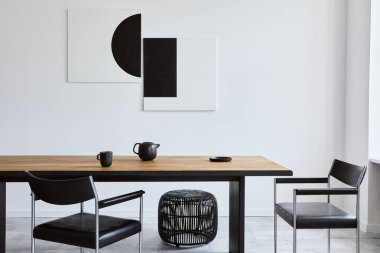 Tasarım ahşap aile masası, siyah sandalyeler, fincanlı çaydanlık, duvarda sanat resimleri ve modern ev dekorunda zarif aksesuarları olan şık bir yemek odası. Şablon.