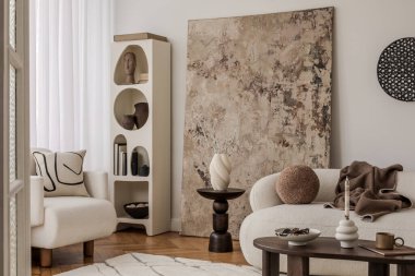 Soyut yastıklı rahat bir köşe, beyaz koltuk ve kırsal desenli duvar sanatı.