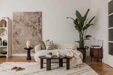 Soyut sanat eserleri, yumuşak tekstil ve toprak aksanlarıyla modern ve doğal stilleri harmanlayan rahat bir oturma odası..