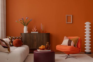 Geometrik yastıkları, turuncu koltuğu ve heykel dekoru olan şık bir iç mekan. Sıcak renkleri ve modern dokunuşları olan cesur, geçmişe dönük bir ortam..