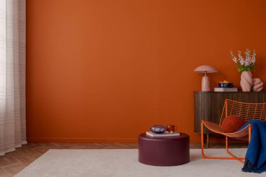 Minimalist ve renkli bir iç mimari, parlak turuncu bir duvar, koyu ahşap bir dolap, ve heykel dekorları. Bordo şalgam ve turuncu tel sandalye modern bir dokunuş ekliyor. Boşluğu kopyala.