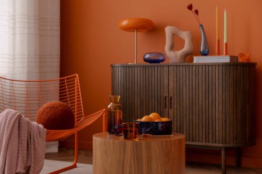 Oturma odasındaki koyu turuncu renkler. Heykel dekorasyonu, sehpa ve koyu ahşap büfe..