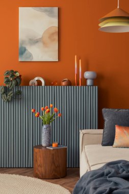 Işınlanmış vazodaki laleler, rahat nötr kanepe ve portakal arkaplanına karşı minimalist sanat eserleri.