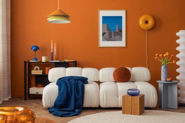 Beyaz çekyatı, turuncu duvarı ve koyu renklerde eklektik dekoru olan modern rahat oturma odası.