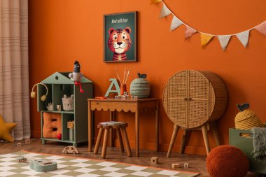 Çocuk masası, rattan dolabı ve renkli bayrağı olan yaratıcı oyun alanı.