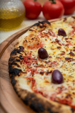 Zeytin yağı ve domateslerle süslenmiş ahşap masada mozzarela peynirli pizza. Pizza margarita.