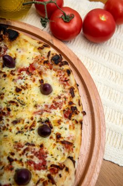 Zeytin yağı ve domateslerle süslenmiş ahşap masada mozzarela peynirli pizza. Pizza margarita.