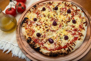 Zeytin yağı ve domateslerle süslenmiş ahşap masada mozzarela peynirli pizza. Pizza margarita.