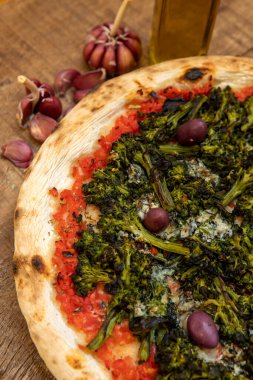 Tahta tahtada servis edilen brokoli pizzası. Mozzarella, brokoli, sarımsak, zeytin ve domates sosuyla pişirilmiş..