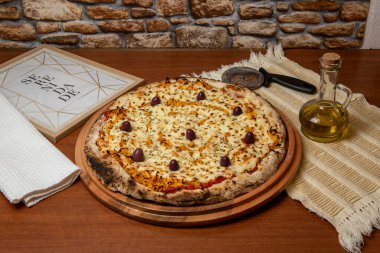 Tahta bir tahtanın üzerinde servis edilen Pizza Tavuk Katupiry aroması. Mozzarella, tavuk, krem peynirli, zeytinli ve kırmızı domates soslu. Bir bardak zeytinyağı. Geleneksel Brezilya pizzası. Portekizce metin: dinginlik