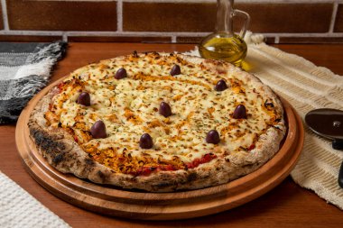 Tahta bir tahtanın üzerinde servis edilen Pizza Tavuk Katupiry aroması. Mozzarella, tavuk, krem peynirli, zeytinli ve kırmızı domates soslu. Bir bardak zeytinyağı. Geleneksel Brezilya pizzası.