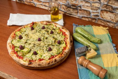Lezzetli İtalyan vejetaryen pizzası, domates sosu, biber, zeytin ve ahşap masa arkasında kabak. Portekizce metin: dinginlik