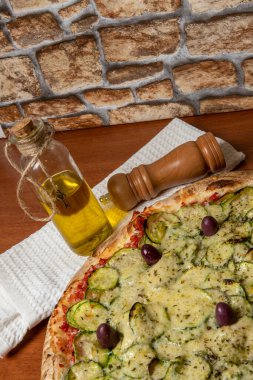 Lezzetli İtalyan vejetaryen pizzası, domates sosu, biber, zeytin ve ahşap masa arkasında kabak. Portekizce metin: dinginlik
