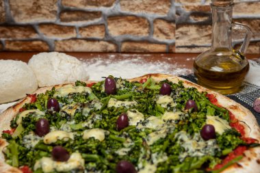 Brokoli, gorgonzola peyniri, siyah zeytin, sarımsak ve domates soslu pizza.