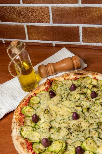 Lezzetli İtalyan vejetaryen pizzası, domates sosu, biber, zeytin ve ahşap masa arkasında kabak. Portekizce metin: dinginlik