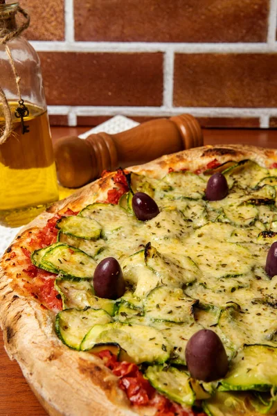 Lezzetli İtalyan vejetaryen pizzası, domates sosu, biber, zeytin ve ahşap masa arkasında kabak. Portekizce metin: dinginlik