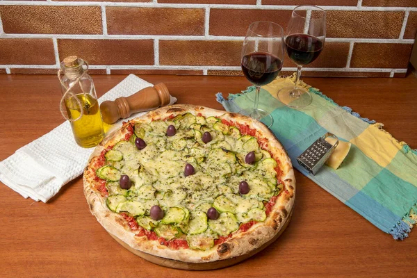 Lezzetli İtalyan vejetaryen pizzası, domates sosu, biber, zeytin ve ahşap masa arkasında kabak..  