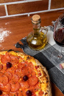 Ahşap masada nefis Pepperoni pizzası. Pepperoni Pizza - Pepperoni, mozzarela peyniri, siyah zeytin ve domates soslu taze pizza