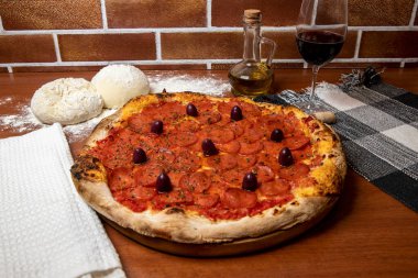 Ahşap masada nefis Pepperoni pizzası. Pepperoni Pizza - Pepperoni, mozzarela peyniri, siyah zeytin ve domates soslu taze pizza