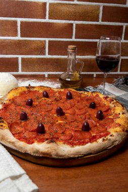 Ahşap masada nefis Pepperoni pizzası. Pepperoni Pizza - Pepperoni, mozzarela peyniri, siyah zeytin ve domates soslu taze pizza