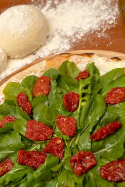 Mozzarella, rucula ve kurutulmuş domatesli pizza.