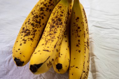 Beyaz kırışık masa örtüsü üzerinde koyu benekli olgun bir muz.